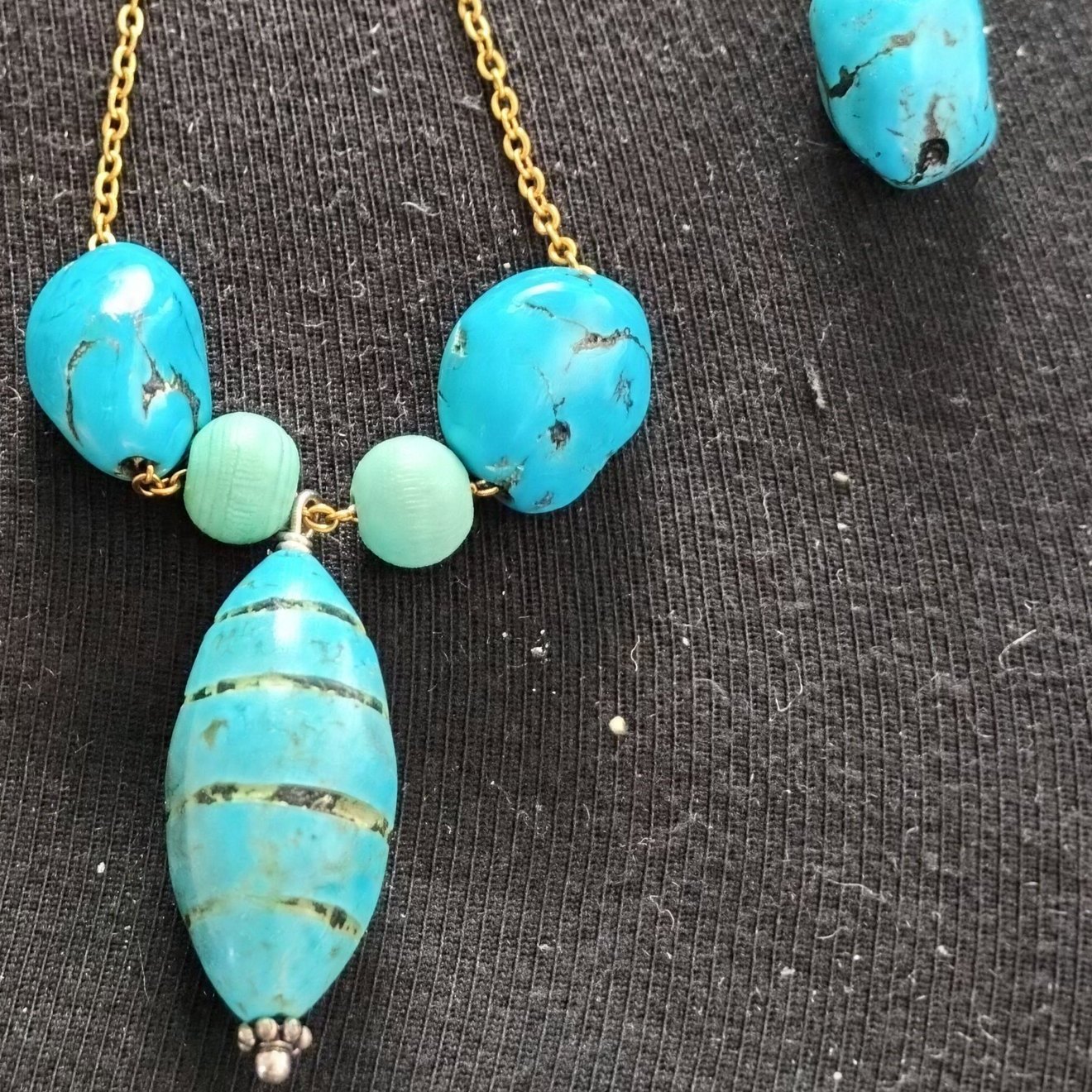 Turquoise beads and a long marbled turquoise bead on a gold chain